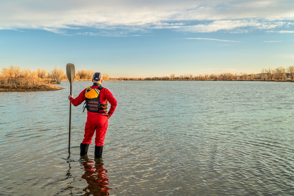 a man wearing a drysuit and holding a paddle 