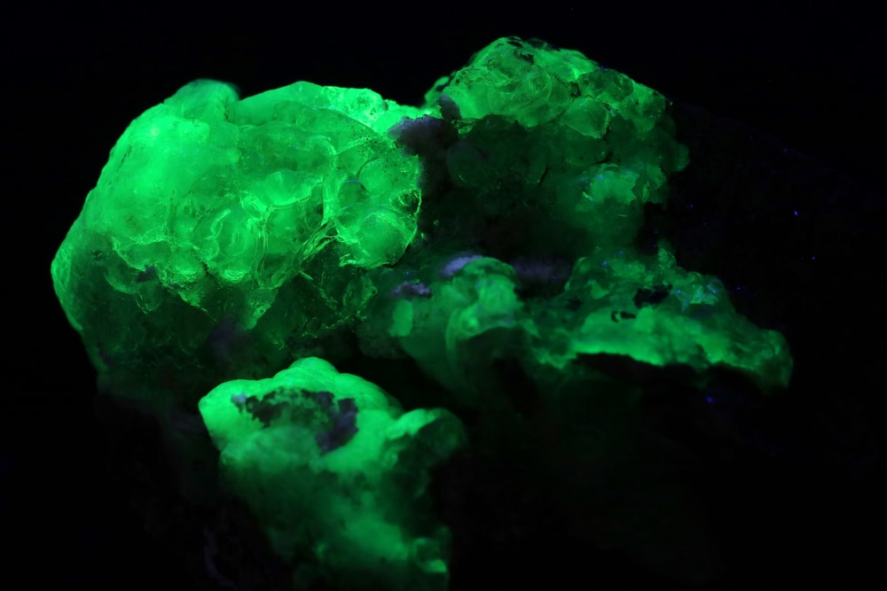 Hyalite Opal shined in green fluorescent on black background