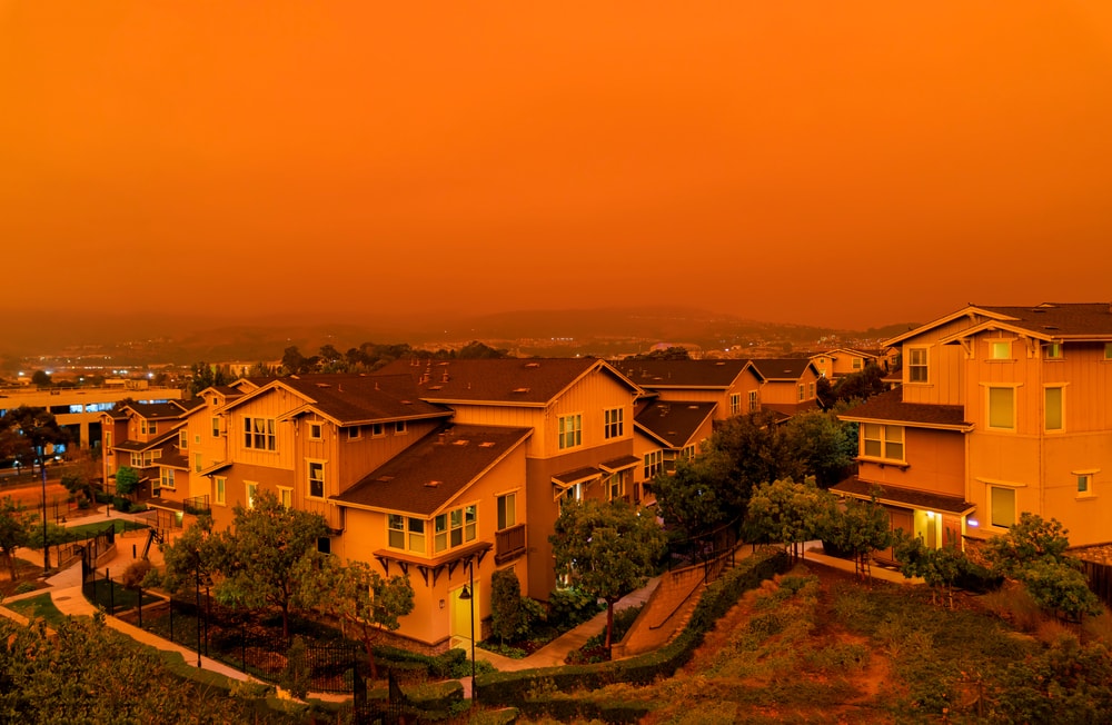 orange sky over houses due to smoke from burning forest