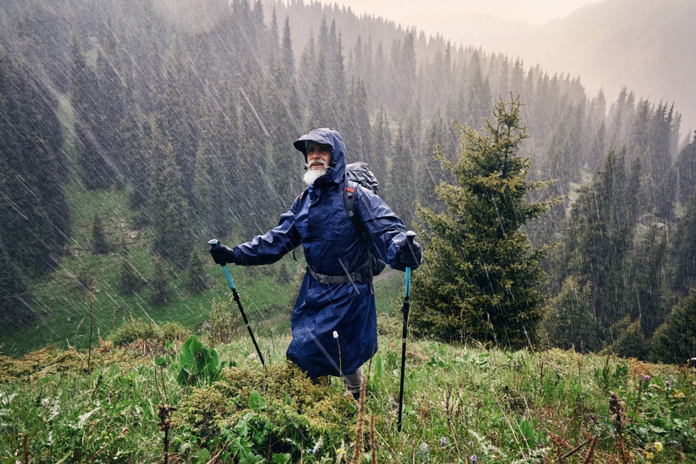 A man wearing a blue raincoat while hiking