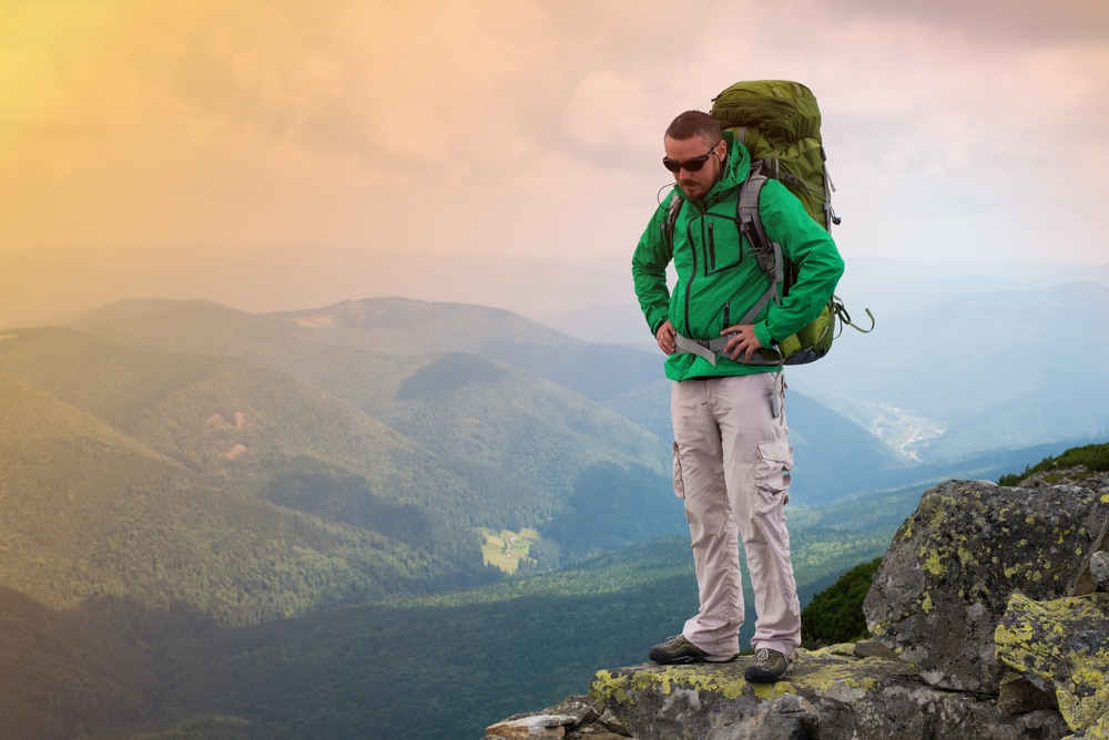 A hiker wearing green jacket and hiking pants with green backpack