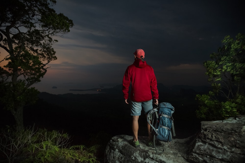 Hiker standing on a cliff at night