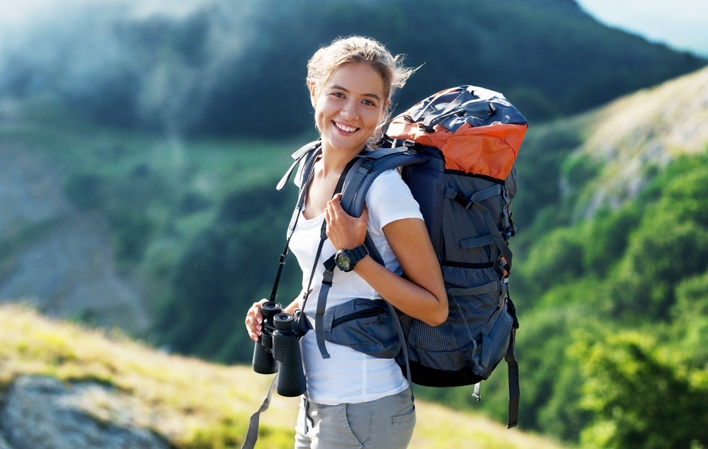 A smiling woman carrying a big backpack on a hike