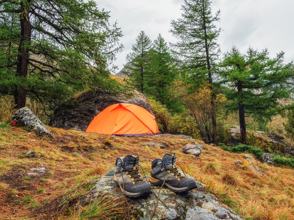 Hiking boots and a tent in a trail