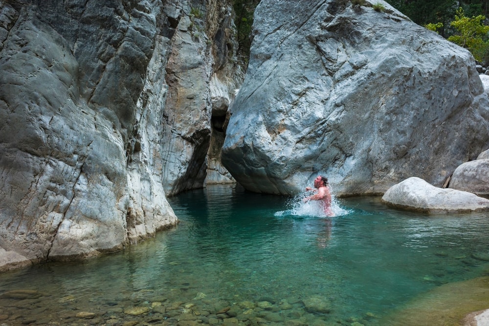 Man taking a dip in clear water of Goynuk river along Lycian way hiking trail