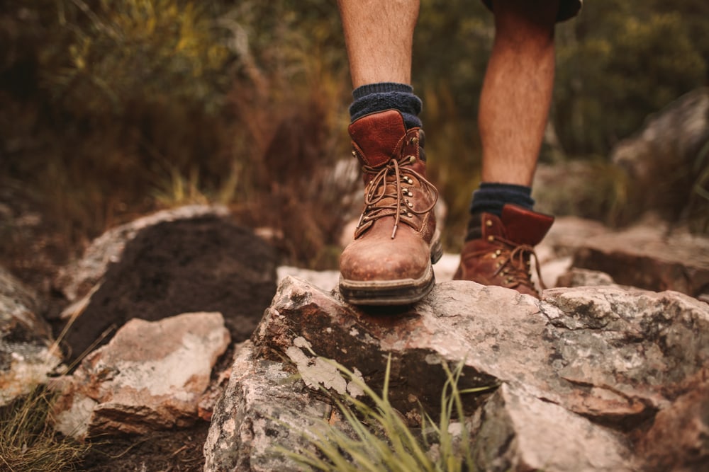Close up of hiking boots stepping on a rocky trail