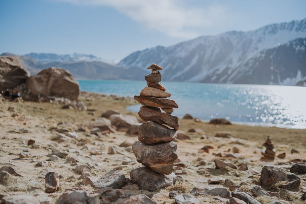 Stacked rocks by the river and view of the alps