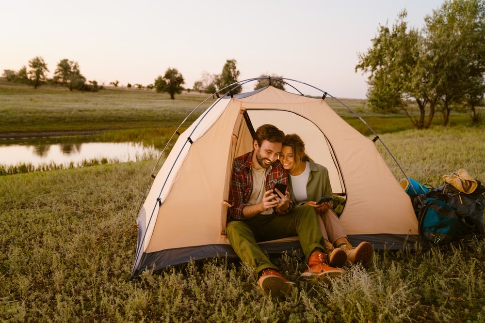 A couple looking at the phone inside their tent