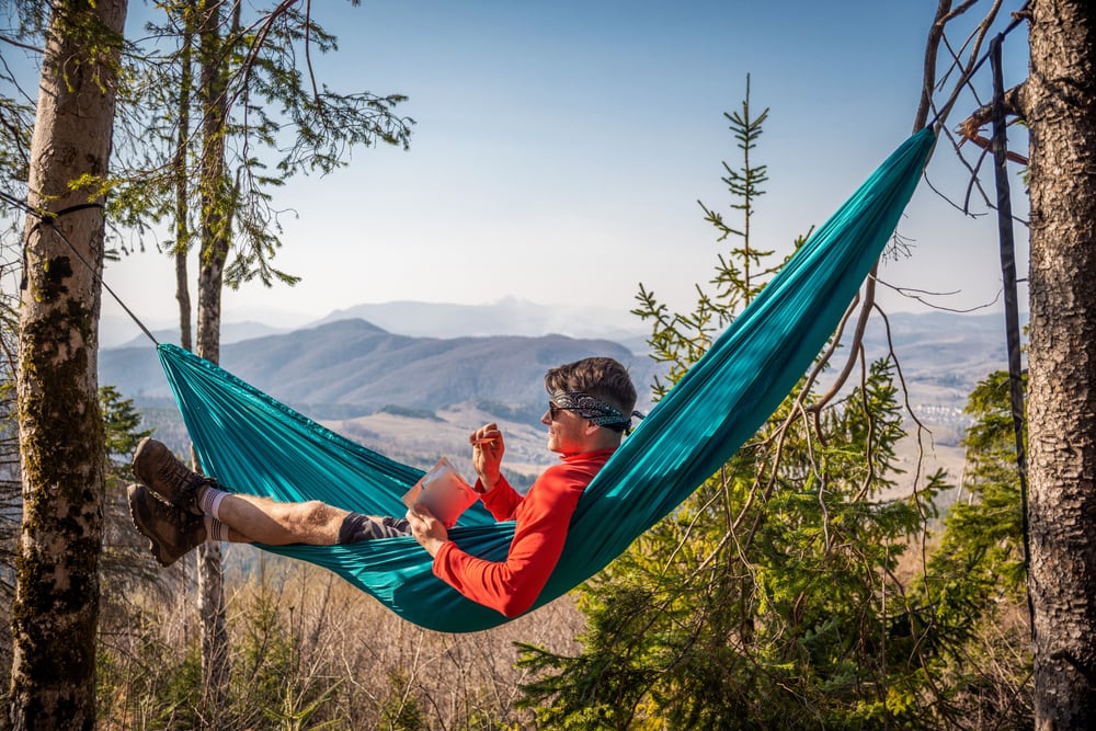 A man resting on a hammock in the mountains