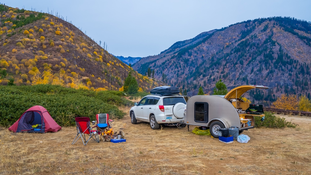 A teardrop trailer and SUV on a campsite