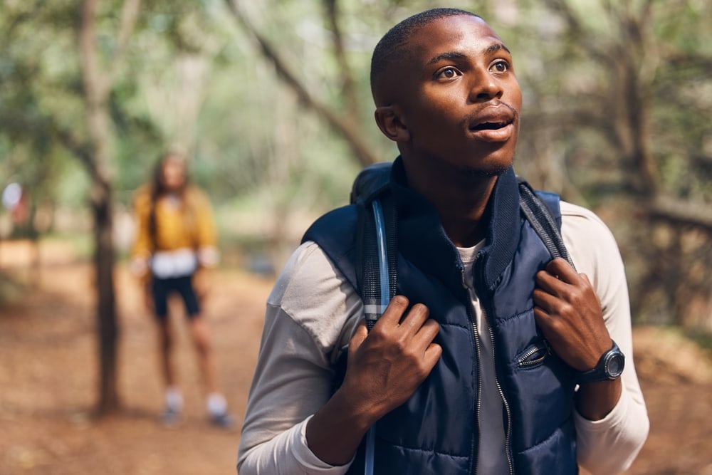 Young man wearing a base layer top and sleeveless puff jacket during a summer hike