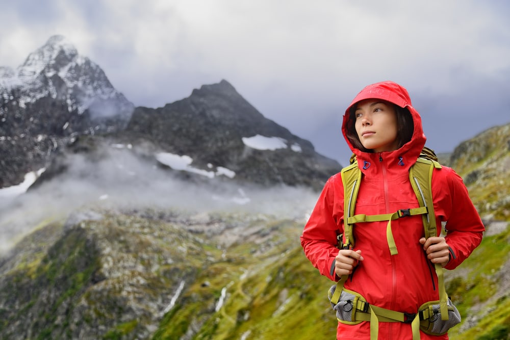 A woman hiker wearing a red hard shell jacket in he Alps