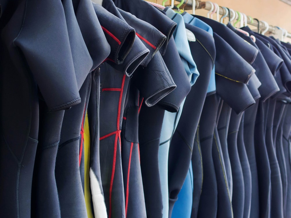 line of hanging of wetsuits made of neoprene material in a diving center