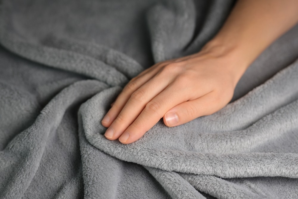 a hand touching a gray fleece blanket